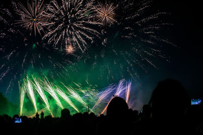 Silhouette crowd against firework display at night