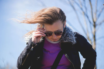 Woman wearing eyeglasses while looking down against sky