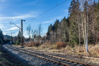 Railway tracks by trees against sky