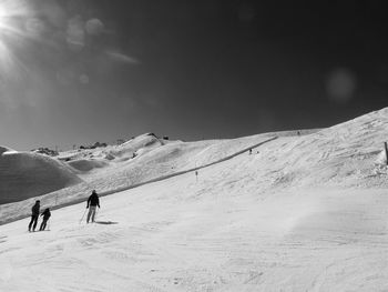 People skiing on snow covered mountain against sky