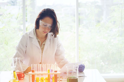 Scientist working at laboratory against window
