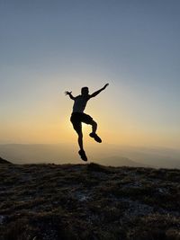 Silhouette man jumping on field