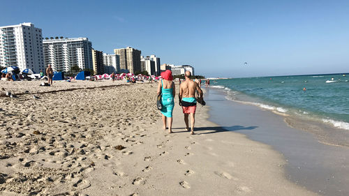 Rear view of women on beach against clear sky