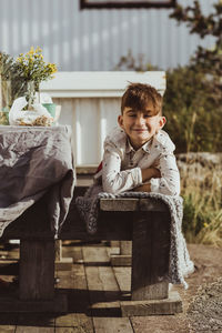 Portrait of boy sitting on wood