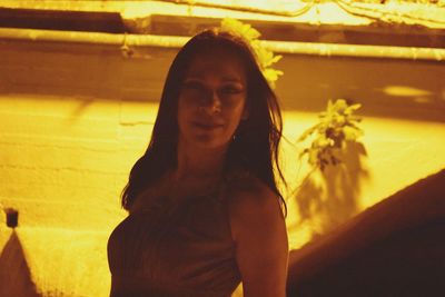 Portrait of beautiful young woman standing against yellow wall