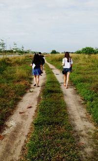 Rear view of people walking on road against sky