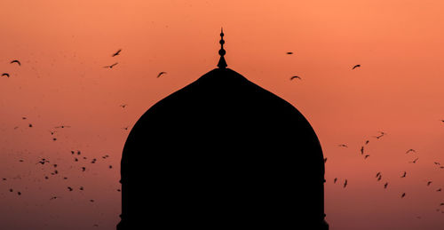 Silhouette birds flying against sky during sunset