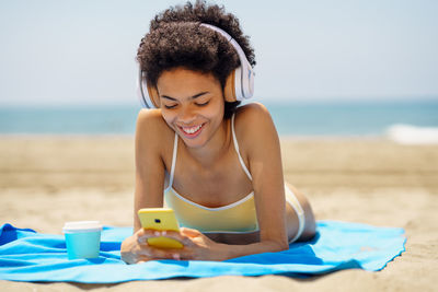 Portrait of young woman using mobile phone at beach