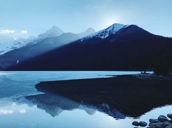 Scenic view of lake by snowcapped mountains against sky