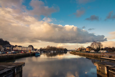 Bridge over river by buildings in city against sky