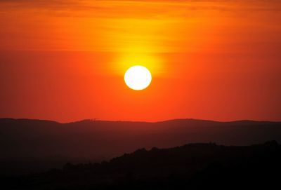 Scenic view of silhouette mountains against orange sky
