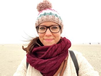Portrait of smiling woman standing at beach during winter