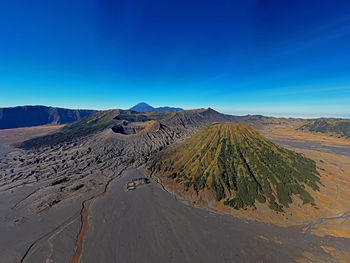 Panoramic view of arid landscape against clear blue sky