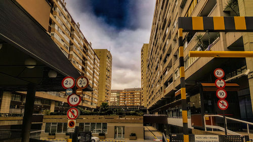 Low angle view of road sign by buildings against sky