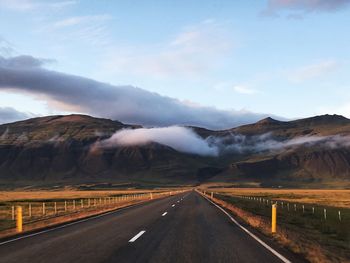 Road leading towards mountains against sky