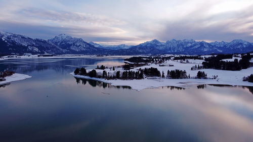 Scenic view of lake by snowcapped mountains against sky