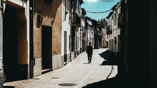 Silhouette people walking on street amidst buildings
