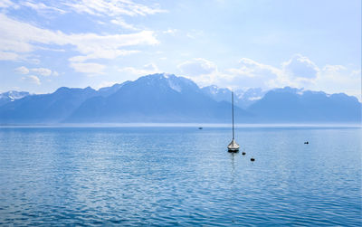 Sailboats in sea against mountains