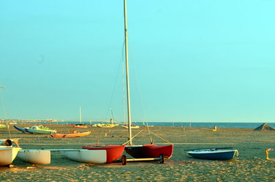 Sailboats moored in sea against clear sky