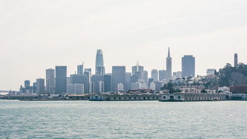 Sea and buildings in city against sky