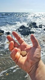 Close-up of hand with sea in background