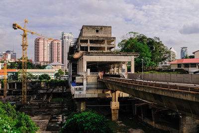 Train on bridge in city against sky