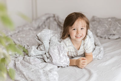 Little cute boy indulges on the bed in the bedroom of the parents at home. 