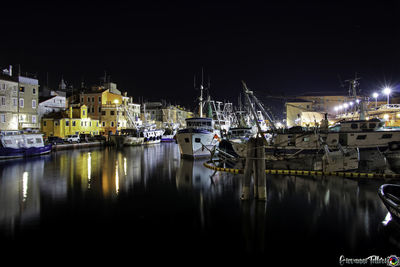 Boats moored in harbor at night