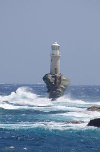 Lighthouse in sea against clear sky