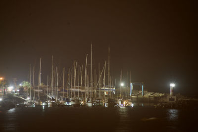 Sailboats moored in harbor at night