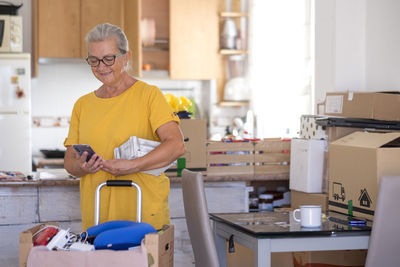 Senior woman using mobile phone while standing at home