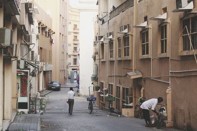 People walking on street amidst buildings in city