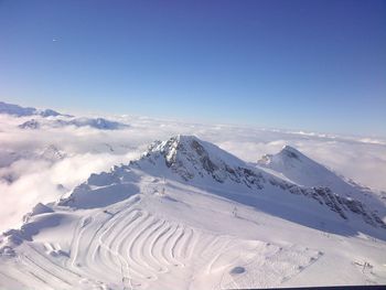 Scenic view of snowcapped mountains against blue sky