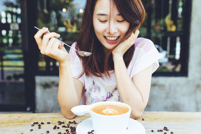 Young woman eating coffee cup on table