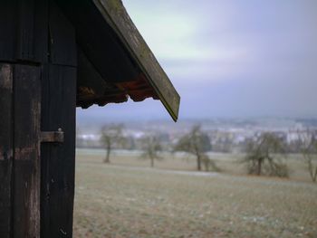 Broken roof of house on field against sky