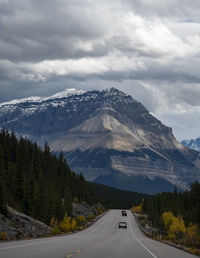 Road leading towards mountains against sky