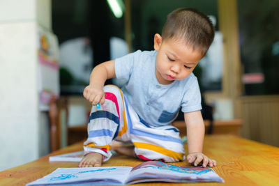 Boy drawing on book at table