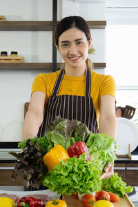 Portrait of smiling woman with vegetables at home