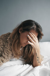 Young woman with head in hands relaxing on bed at home