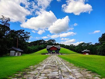 Houses on field by building against sky