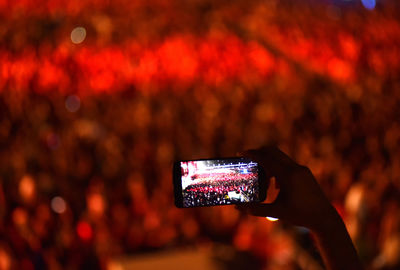 Cropped hand photographing crowd