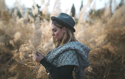 Side view of woman wearing hat standing on field