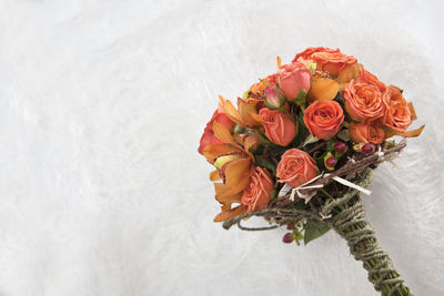 Close-up of orange rose bouquet against white wall