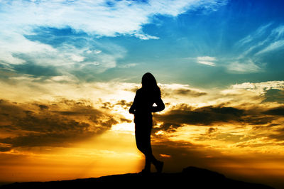 Silhouette woman standing on mountain against sky during sunset