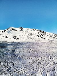 Scenic view of snow covered mountains against clear blue sky
