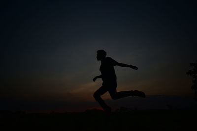 Silhouette man running on field against sky during sunset