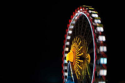 Low angle view of illuminated ferris wheel spinning against sky at night