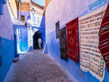 Rear view full length of man walking amidst walls at alley