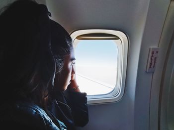 Woman looking through window in airplane