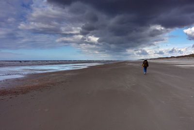 Rear view of person on beach against sky